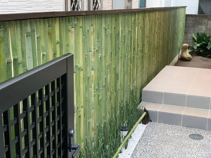 Bamboo fencing along a ground-level passage beside a home