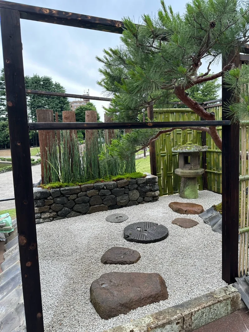 Stepping stones, gravel and bamboo fencing in a ground-level Japanese-style garden